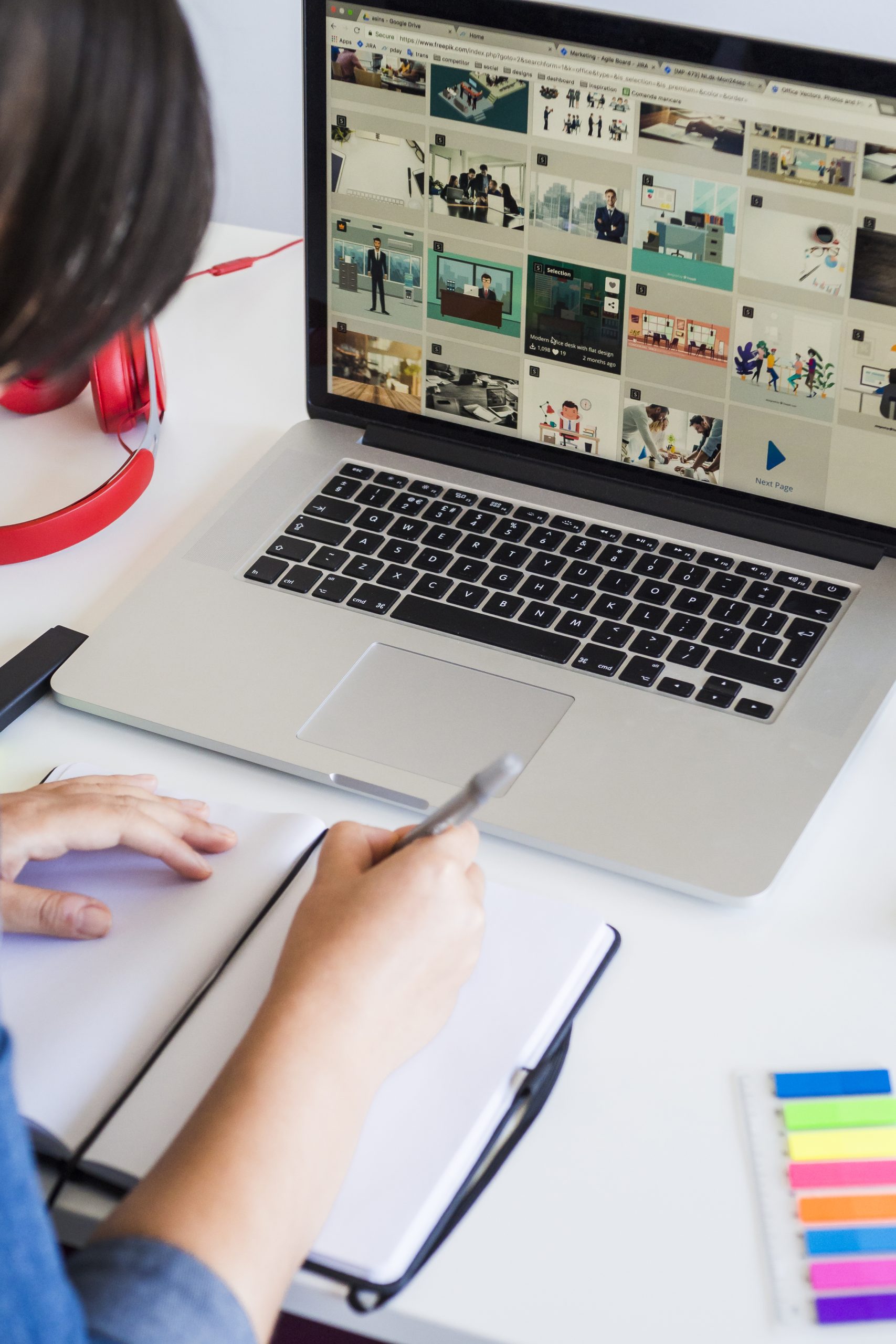 woman taking notes near laptop headphones table